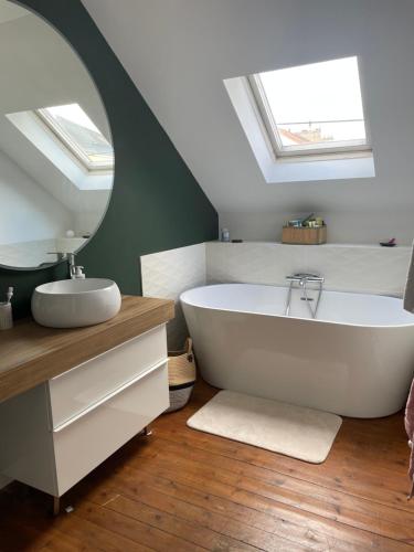 La salle de bains est pourvue d'une baignoire blanche et d'un miroir. dans l'établissement logement entier proche centre ville et circuit, au Mans