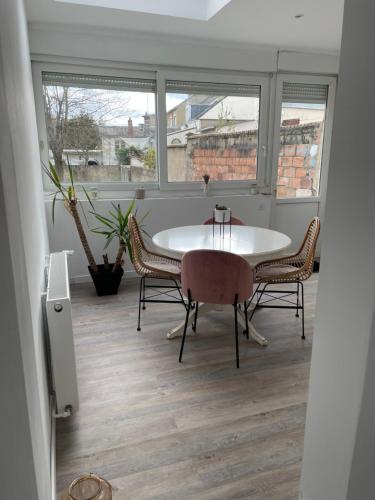 une table et des chaises dans une pièce avec des fenêtres dans l'établissement logement entier proche centre ville et circuit, au Mans