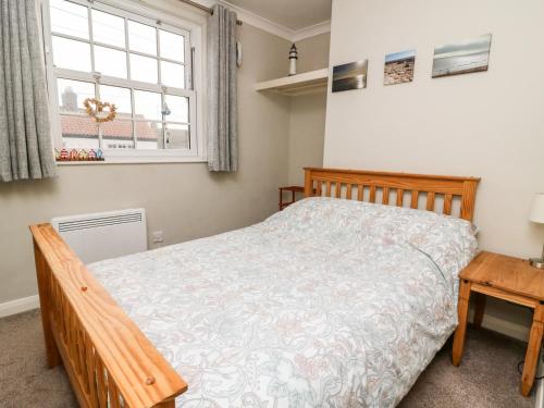 una camera da letto con un letto di legno e una finestra di Keepers Cottage, 21 Coppergate a Nafferton