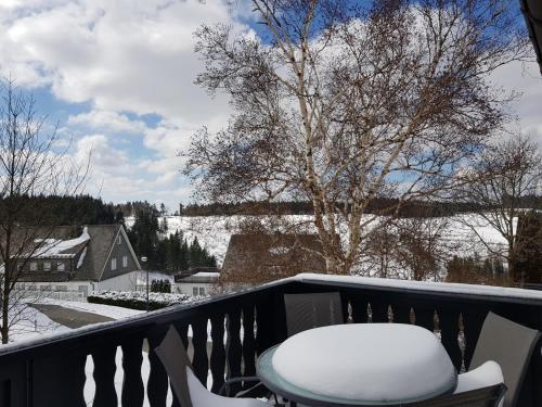 a snow covered chair on a balcony with snow on the ground at Altastenberger Lodge in Winterberg