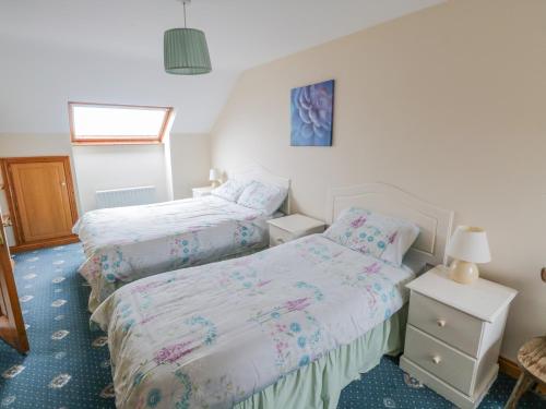 a bedroom with two beds and a window at Quayside House in Roundstone