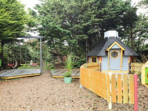 a playground with a small house and a swing at Sutton Cottage in Broadway
