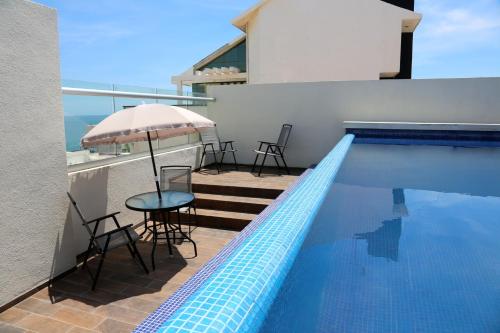 a swimming pool with a table and chairs and an umbrella at EMS Hoteles Boca del Río in Veracruz