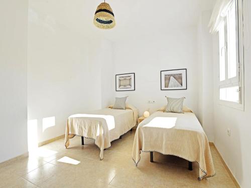 a white room with two beds and a window at Apartamentos Santiago in Écija