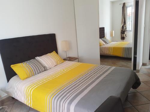 1 Schlafzimmer mit 2 Betten mit gelber und grauer Bettwäsche in der Unterkunft Maison de Line in LʼÎle-dʼOlonne