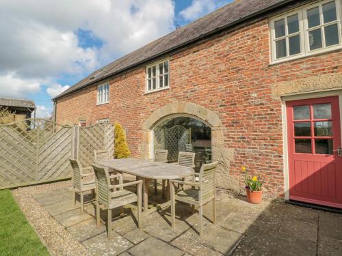 a patio with a table and chairs in front of a brick building at The Red Barn in Longframlington