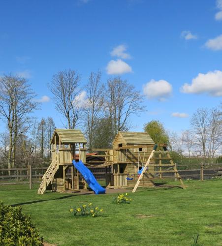 a wooden playground with a slide and a play structure at Hoeve Chartreuse in Bruges