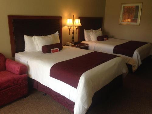 a hotel room with two beds and a red couch at Ramada by Wyndham Sunnyvale/Silicon Valley in Sunnyvale