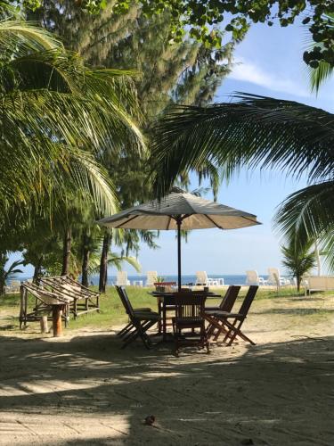 a table and chairs under an umbrella on the beach at Kahanbu Ocean View in Thulusdhoo