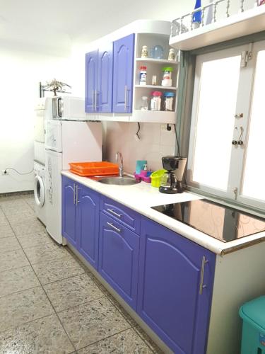 a kitchen with blue cabinets and a sink at Apartment & Beach - Airport in Playa del Burrero