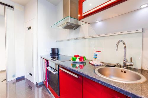 une cuisine avec des armoires rouges et un évier dans l'établissement LE TIVOLI AP4264 By Riviera Holiday Homes, à Nice