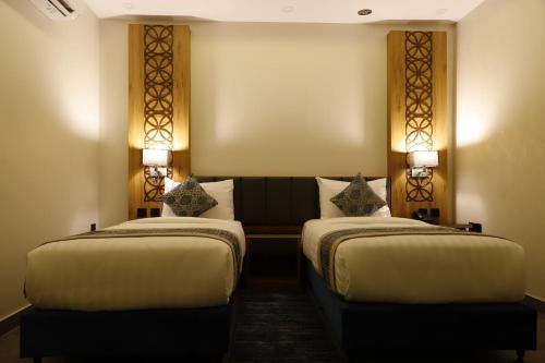 two beds in a hotel room with two lamps at PRIMOTEL Elite As Salamah - Serviced Apartments in Jeddah