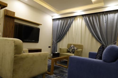 a living room with two chairs and a flat screen tv at PRIMOTEL Elite As Salamah - Serviced Apartments in Jeddah