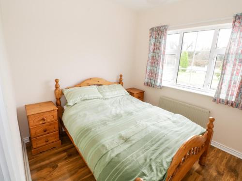 een slaapkamer met een bed en een raam bij Dromore West Cottage in Dromore West