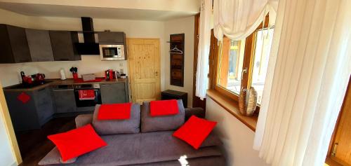 - un salon avec un canapé et des oreillers rouges dans l'établissement Sonniges Eck Ferienwohnung 2, à Rathen