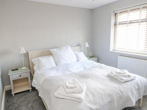 Un dormitorio blanco con una cama blanca con toallas. en Keeper's Cottage, en Moelfre
