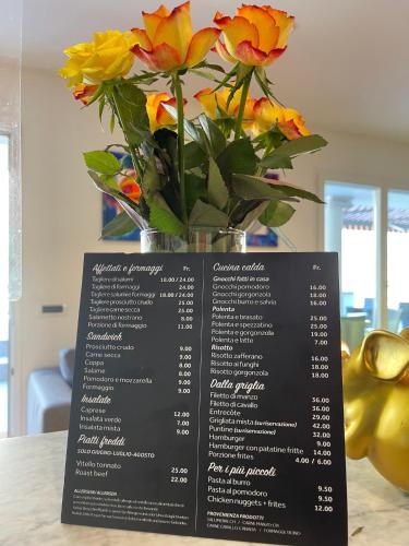 a vase of flowers sitting on top of a menu at Hotel al Ponte Antico in Intragna