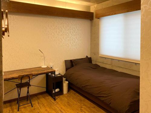 a bedroom with a bed and a desk and a window at Kugani-YA. in Kin
