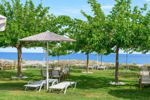 a group of chairs and umbrellas on the grass near the ocean at Castello Antico Hotel in Gythio