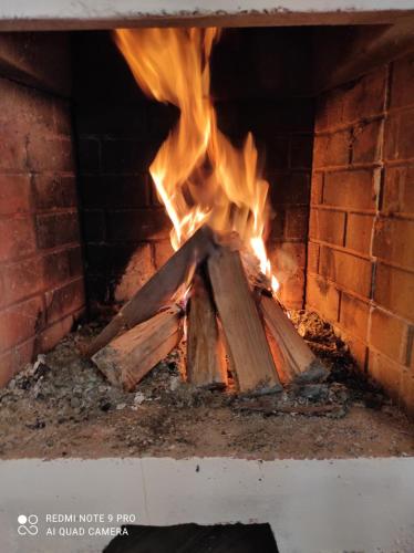 a fire in a brick oven with flames at Chalé Lavanda com Hidro, Trilhas e Cachoeiras in São Francisco Xavier