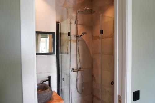 uma casa de banho com um chuveiro e uma porta de vidro em Allé på Österlen em Kivik