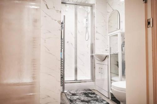 a white bathroom with a toilet and a window at S.H Apartments in Glasgow