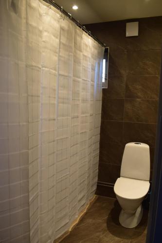 a bathroom with a toilet and a white tiled wall at Villa Enigma in Halmstad