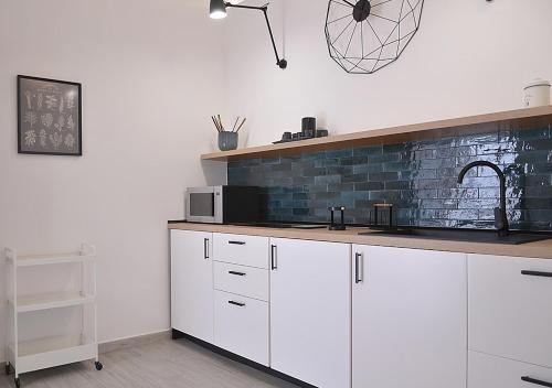 a kitchen with white cabinets and a brick wall at The Court Suites & Spa in Taranto