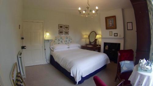 a bedroom with a large white bed and a chandelier at Wood House in Cockermouth