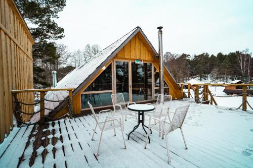 a deck with chairs and a table in front of a cabin at Viesu nams Melnsils in Melnsils