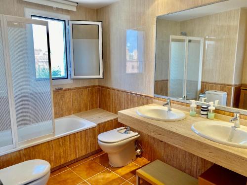 a bathroom with two sinks and a toilet and a tub at Casa con vistas al mar in El Vendrell