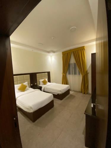 two beds in a room with yellow curtains at شقق ركن مدهال جازان للشقق المخدومة in Jazan