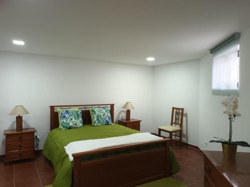 a bedroom with a bed with green sheets and a window at Casinha Alice in Nazaré