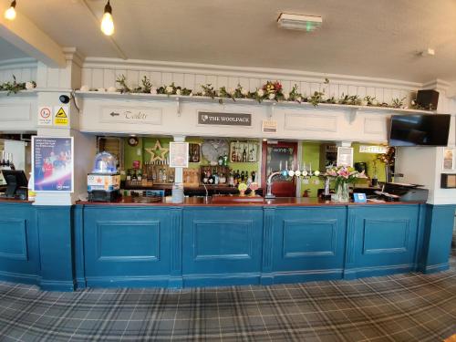 a bar with blue cabinets and flowers on the wall at Woolpack Inn in Chichester