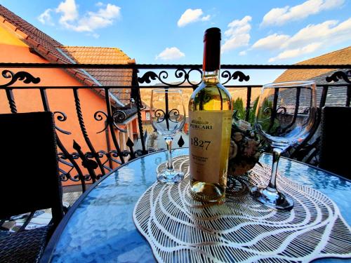 a bottle of wine sitting on a table with two glasses at Virág Panzió in Lupeni