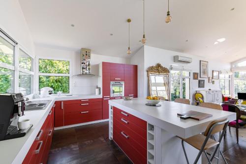 une cuisine avec des armoires rouges et un comptoir blanc dans l'établissement Bains de Lumière, à Moëlan-sur-Mer