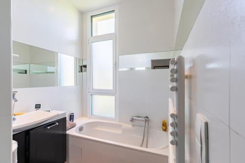 une salle de bain blanche avec une baignoire et un lavabo dans l'établissement Bains de Lumière, à Moëlan-sur-Mer