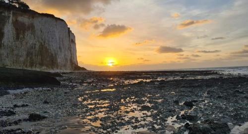 a sunset on the beach with the sun setting at Studio à la mer in Criel-sur-Mer