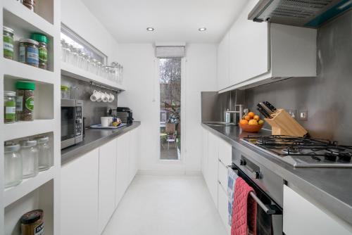 a kitchen with white cabinets and a stove at Captivating apartment in Shepherds Bush in London