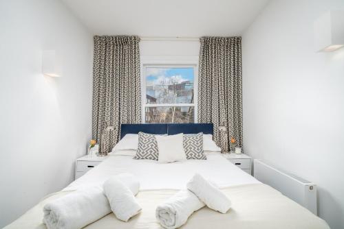 a bedroom with a white bed with towels on it at Captivating apartment in Shepherds Bush in London