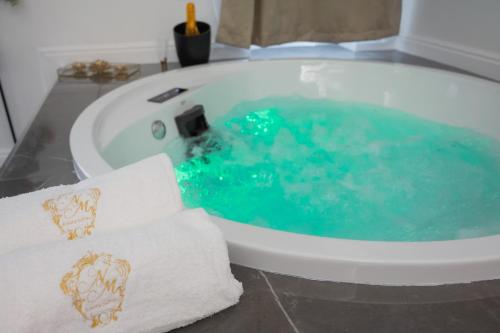 uma banheira cheia de água azul na casa de banho em NM Luxury Suites em Pompeia