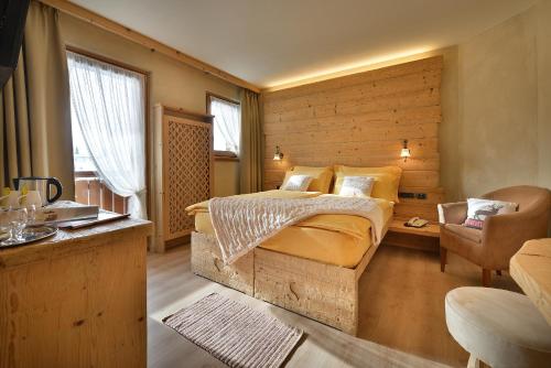a bedroom with a bed and a wooden wall at Hotel Costanza Mountain Holiday in Livigno