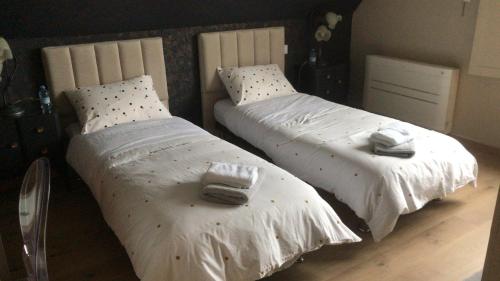 2 camas en un dormitorio con sábanas blancas y toallas en Les coquelicots - Chambre Marie, en Houdan