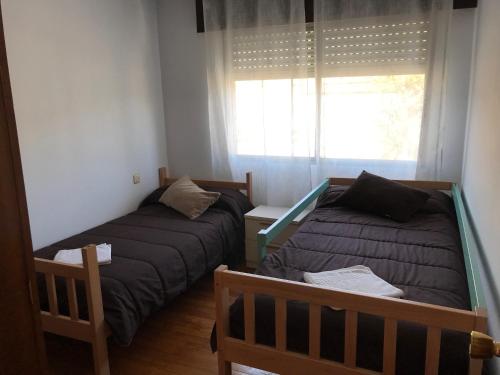 a bedroom with two beds and a window at PENSIÓN LA HACIENDA in Padrón