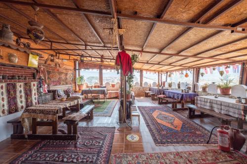 Cette grande chambre comprend des tables, des chaises et des tapis. dans l'établissement Anz Guest House Pansiyon, à Selçuk