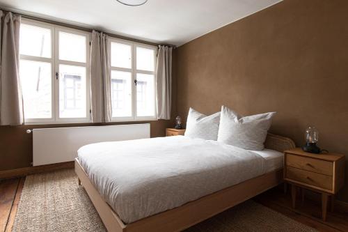 a bedroom with a bed with white sheets and two windows at Ferienwohnung Lukas - Lehm erleben in Tangermünde