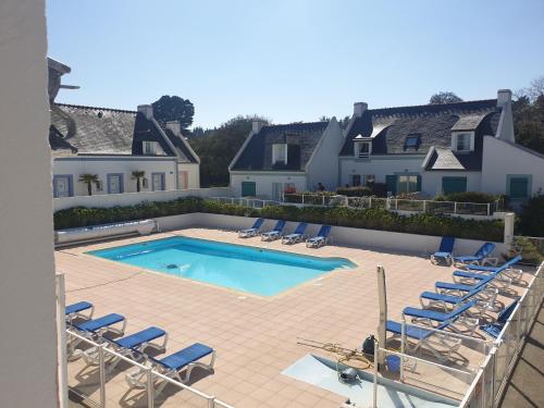 une piscine avec des chaises longues et une maison dans l'établissement Locations LOC'MARIA - Location Professionnelle, à Locmaria