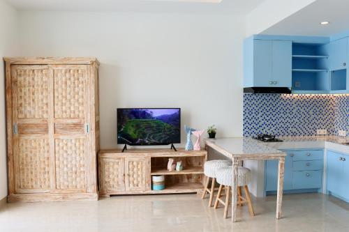 a kitchen with blue cabinets and a table and a tv at Ocean Star Apartment Sanur in Sanur