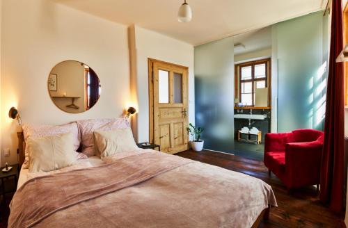 a bedroom with a large bed and a red chair at Baroque chaplain house Kaplanka 1796 A. D. - historical luxury apts in Bohemian Paradise in Železný Brod