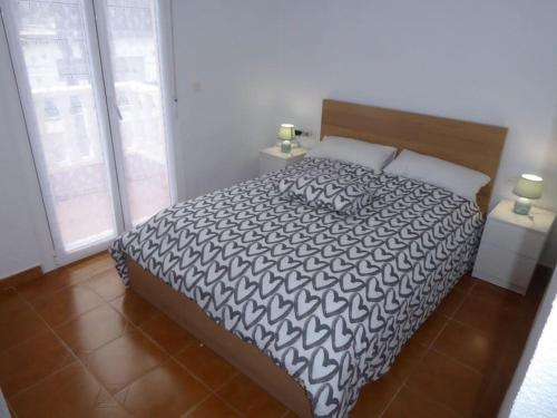 a bedroom with a bed with a black and white comforter at Maison rénovée à 250m de la mer in Santiago de la Ribera